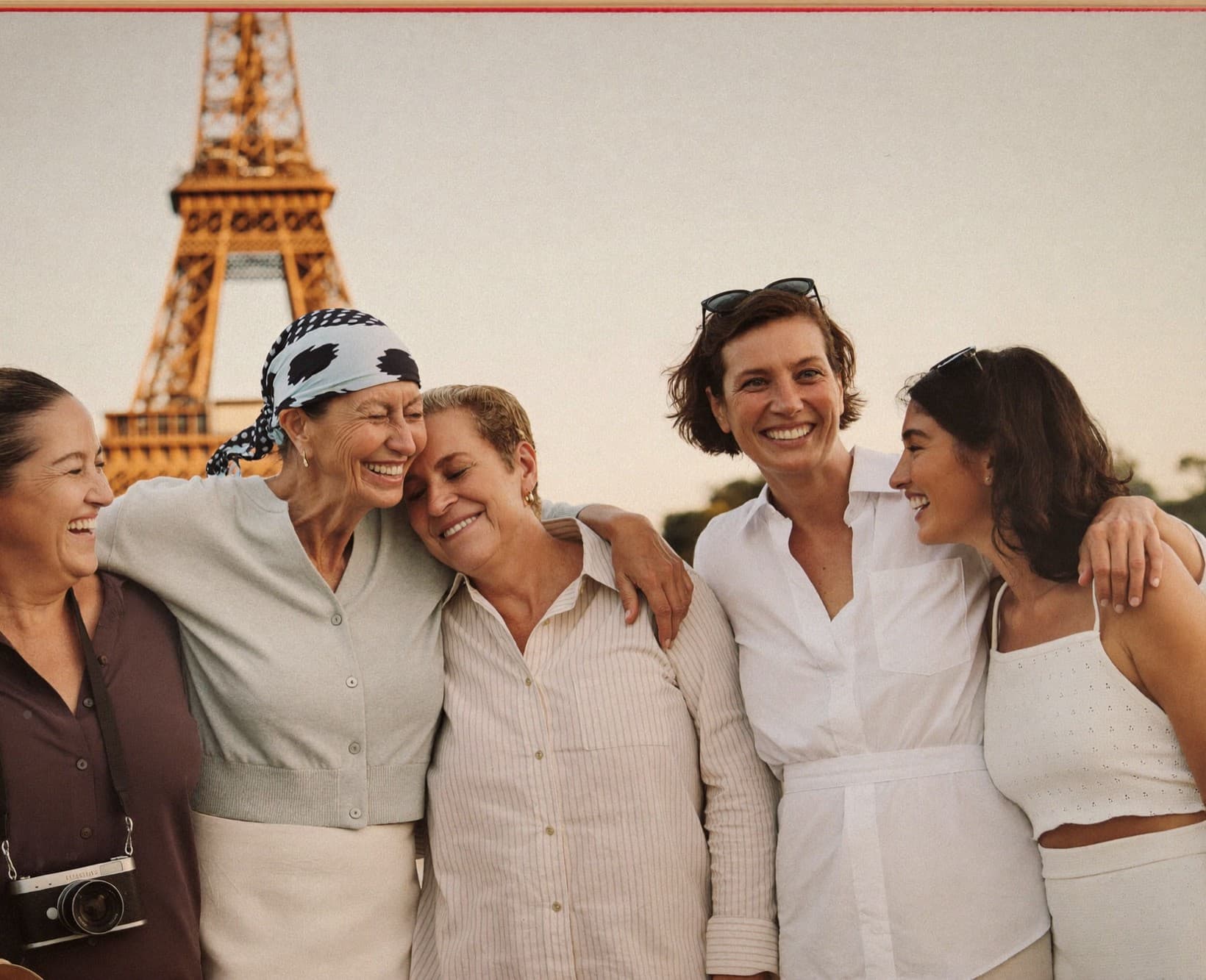 Cinco mujeres riéndose juntas con la Torre Eiffel detrás