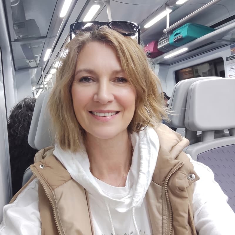 Nora, sonriendo, sentada en un tren